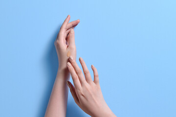 Woman Applying Cream to Hands on Blue Background
