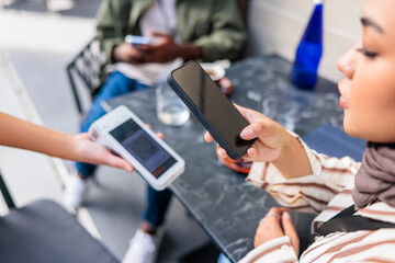 Closeup of woman scanning card reader through smartphone for payment