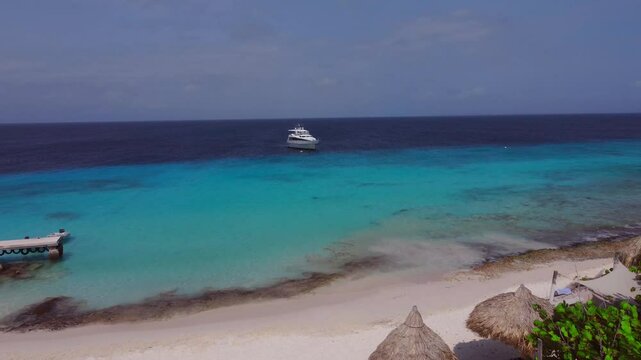 White Yacht in Caribbean Island Water at Beach with palapas