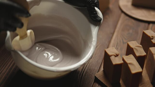 Person mixes the soap mass in the process of making soap. The master mixes the ingredients in the workshop