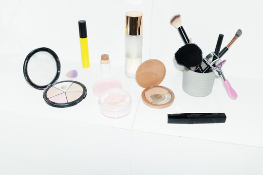 Collection of makeup: bronzer, powder, highlighter, glitter, mascara