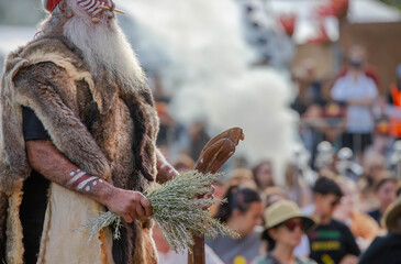 Human hands hold wooden dish with Australian plant branches, the smoke ritual rite at a indigenous...