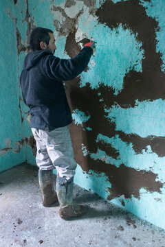 Worker rebuilds adobe wall.