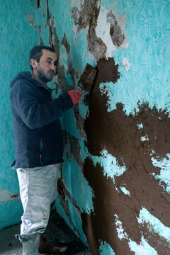Worker rebuilds adobe wall.