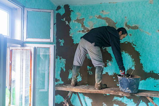 Worker rebuilds adobe wall.