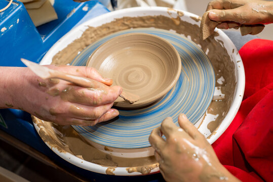 Children's and adults' hands in clay, clay plate on a potter's wheel