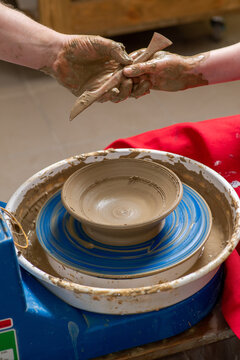 Children's and adults' hands in clay, clay plate on a potter's wheel