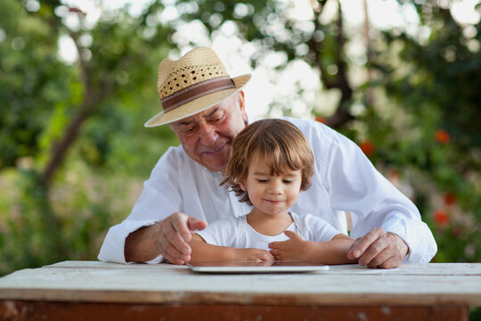 Grandfather and grandson enjoying time together with a tablet outdoors