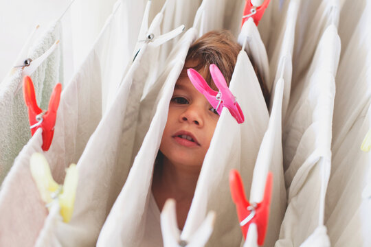 Child Playing Among Hanging Laundry
