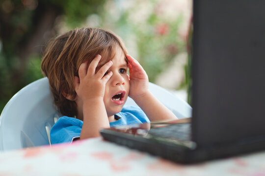 Scared child sitting at a table during computer session