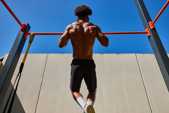 Muscular man doing exercises on sports ground