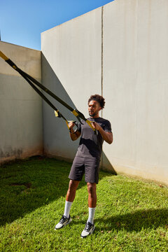 Black man exercising trx in park