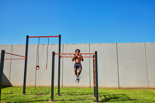 Young man hanging on bars doing pull ups
