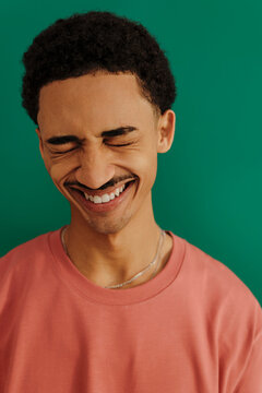 Man wearing pink t shirt smiling in green backdrop