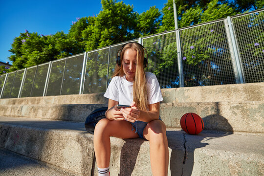 Woman with smartphone on sportsground