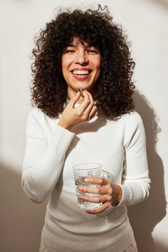 Smiling woman taking fish oil supplement with water