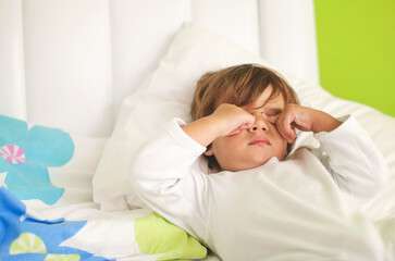 Small child waking up in a cozy bed on a bright morning