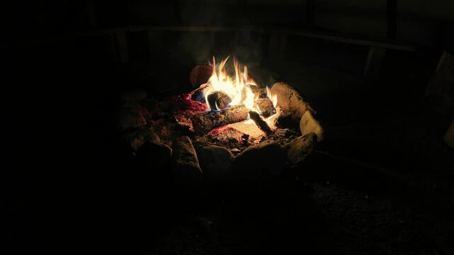 Burning wood at a campsite in a rock firepit bonfire inside of a tipi 
