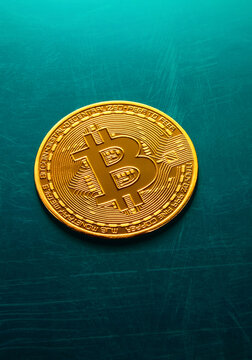 Golden bitcoin coin on a textured blue surface. 