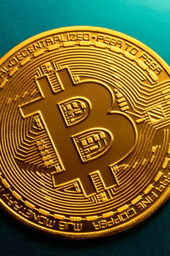 Golden bitcoin coin on a textured blue surface. 