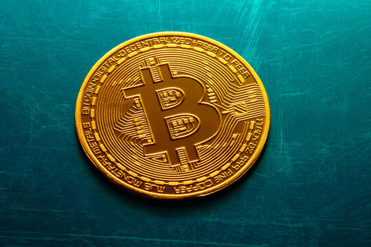 Golden bitcoin coin on a textured blue surface. 