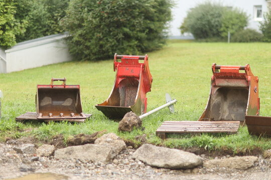 Three red construction tools are sitting on a grassy field