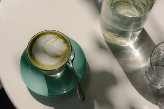 Delicate latte art on a matcha latte in a green cup