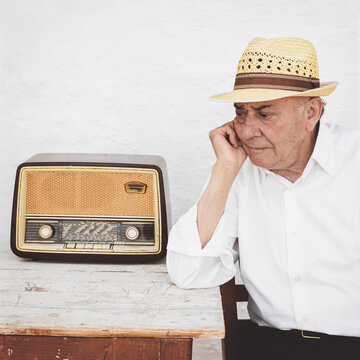 Elderly man listening to vintage radio on a sunny day