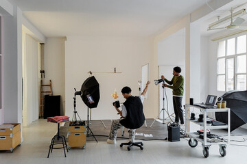 Photographers working in professional studio with lighting equipment