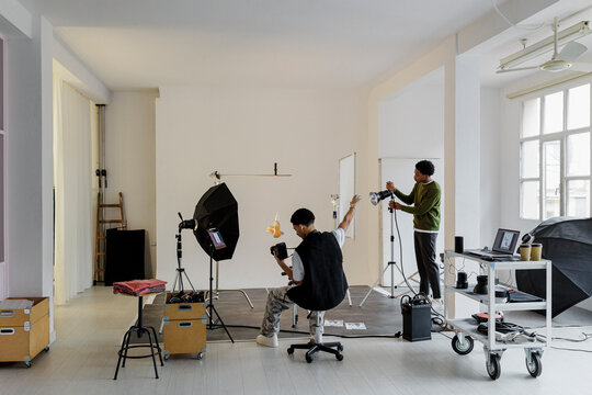 Photographers working in professional studio with lighting equipment