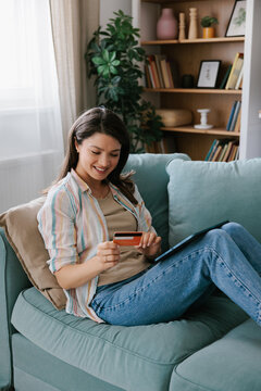 Woman Shopping Online using credit card While Relaxing on Sofa  