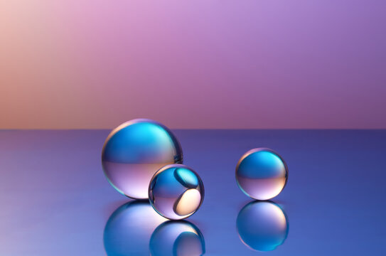 Three glass spheres on reflective gradient purple background. 