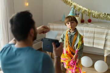 Dad takes a Polaroid photo of the birthday boy