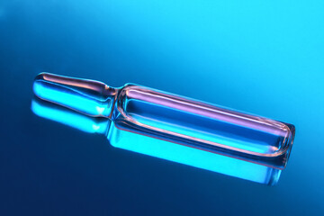 Clear glass ampule with medicine on a gradient blue purple background