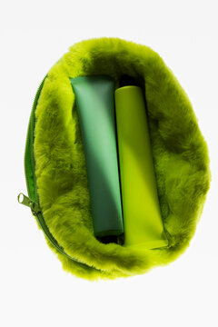Bright green fluffy cosmetic bag with colored tubes of cream