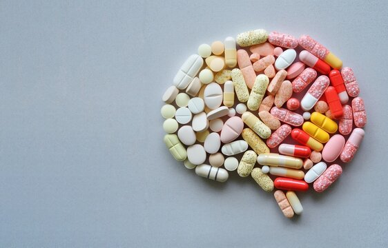 A brain shape made from pills, tablets, and capsules on a minimalist white background. Perfect for brain injury, healthcare, medical, mental health awareness, or pharmaceutical industry visuals.