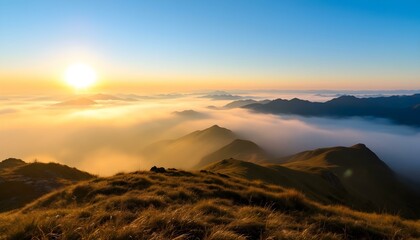 Naklejka premium Sunrise over misty mountain range with golden grassy slopes, blue sky, and distant peaks fading into the horizon.