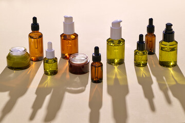 Assorted Cosmetic Serum Bottles on Yellow Surface With Shadows