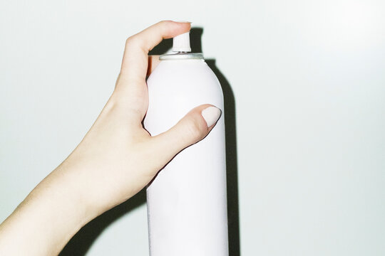 Hand holding a beauty product spray bottle with hard direct flash