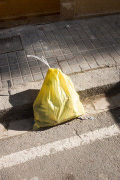 Yellow plastic rubbish trash bag on street in urban city environment