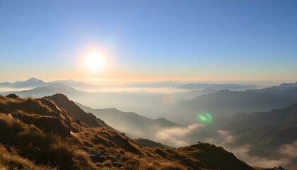 Sunrise over misty mountain range with golden grassy slopes, blue sky, and distant peaks fading into the horizon.