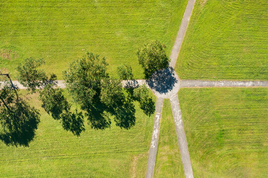 Aerial view of a grassy park with intersecting paths and trees
