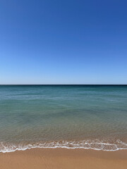 empty beach and calm sea against clear blue sky with space for text