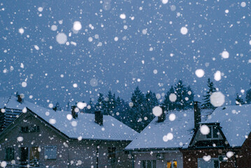 Winter landscape with snowfall and cozy tiled roofs of houses 