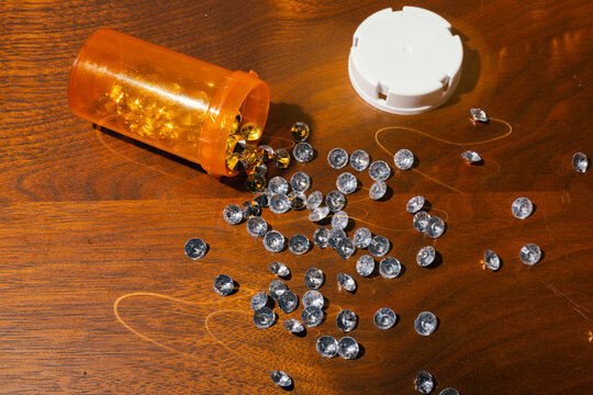 Faux diamonds spilling out of orange prescription pill bottle