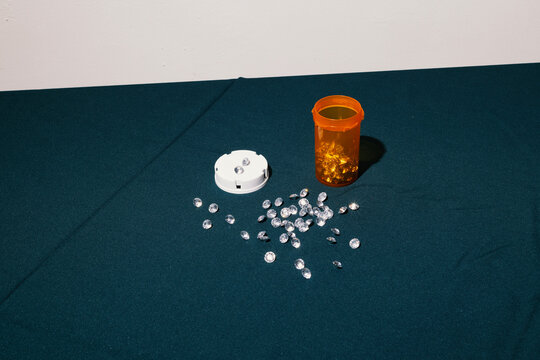 Spread of diamond pills next to open prescription bottle on tabletop