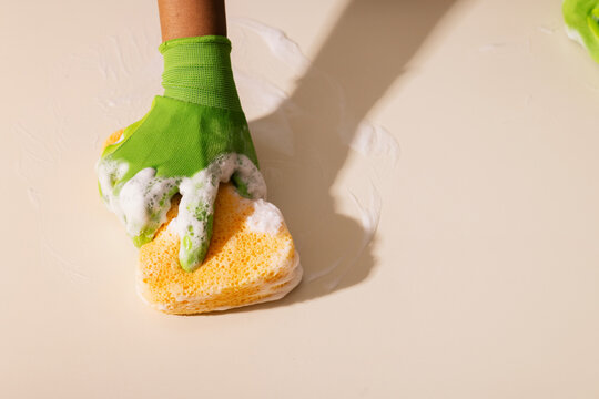 Anonymous hand cleaning a kitchen counter with green gloves