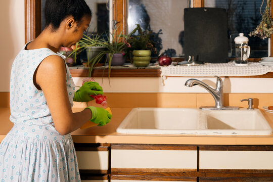 Young Woman Applying soap to a Sponge by a Retro Sink