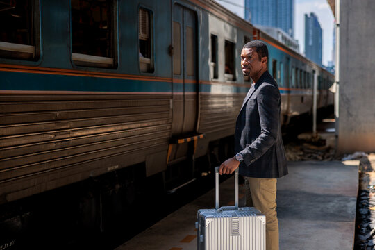 Businessman with luggage standing in front of train