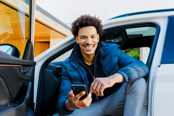 Smiling man using smartphone in his car